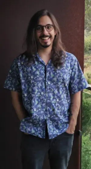 João Dias outside, on a sunny day, wearing a hawaiian shirt and smiling at the camera.